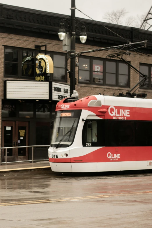 a red and white city tram parked in front of a building