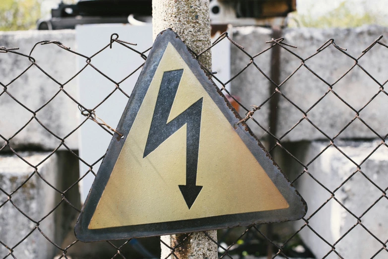 a warning sign mounted on a metal fence