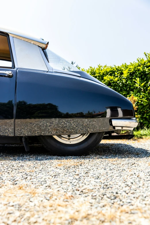 an old classic car is shown in front of some shrubs