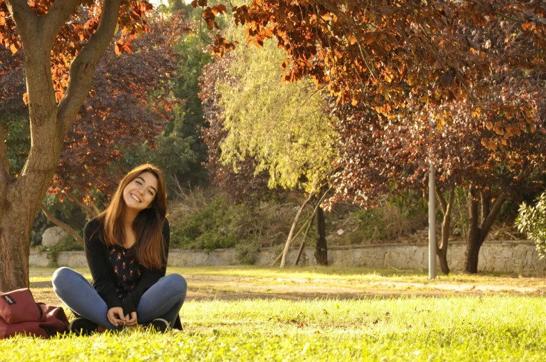 a woman sits on the grass and smiles