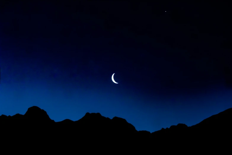 a night scene with a crescent and moon, in the middle of a dark blue sky