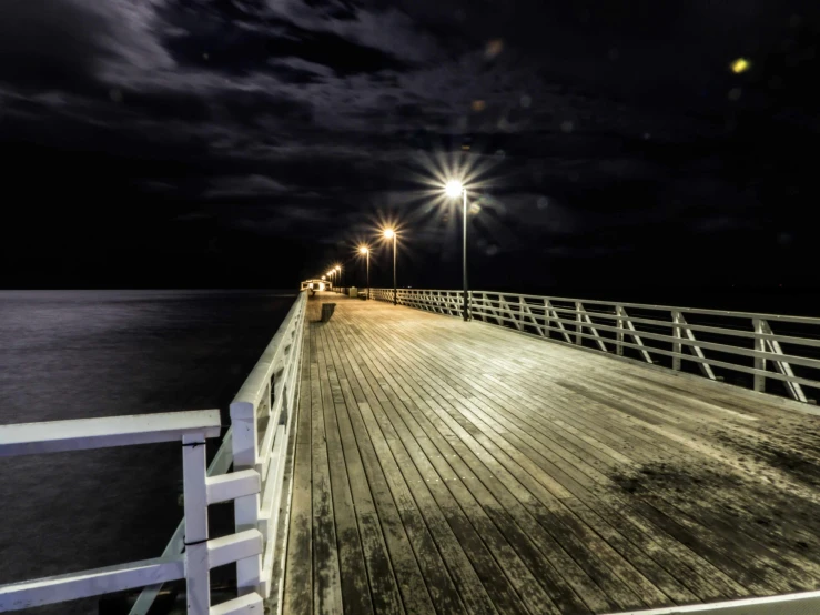 a light at the end of a pier looking down into the ocean