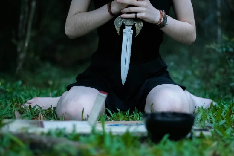 girl in black dress with a sword sitting on the ground
