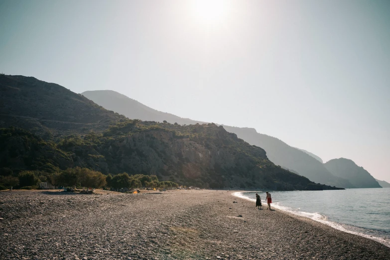 two people are standing in the sun by the water