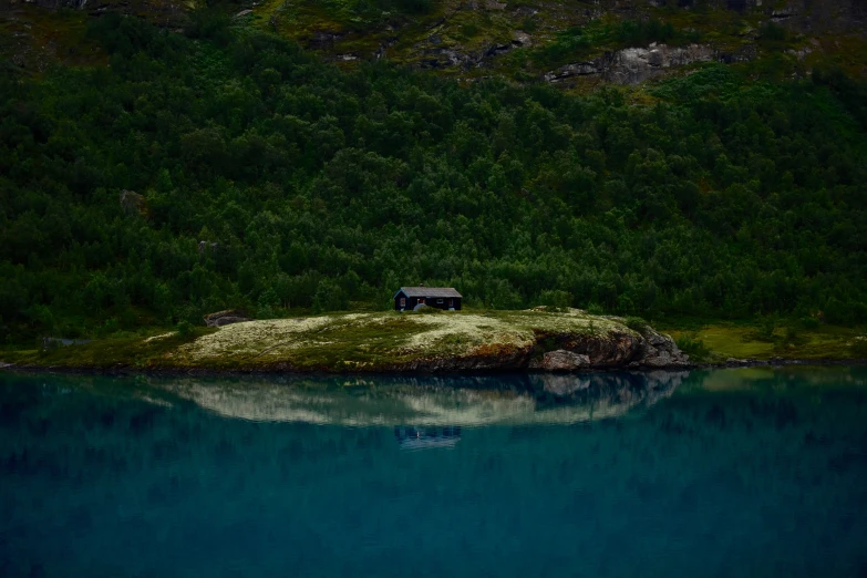 a hill is above the water with a house on top