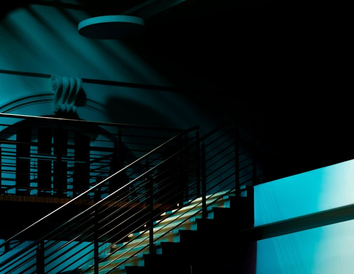 a black stairs in a blue room with blue lighting coming from the wall