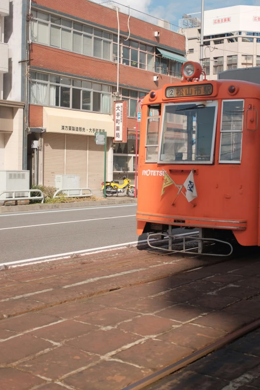 an orange streetcar is driving down the road