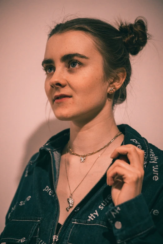 a woman in a denim shirt holding onto a necklace