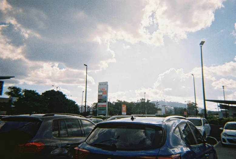 the sky and cars are parked outside of a gas station