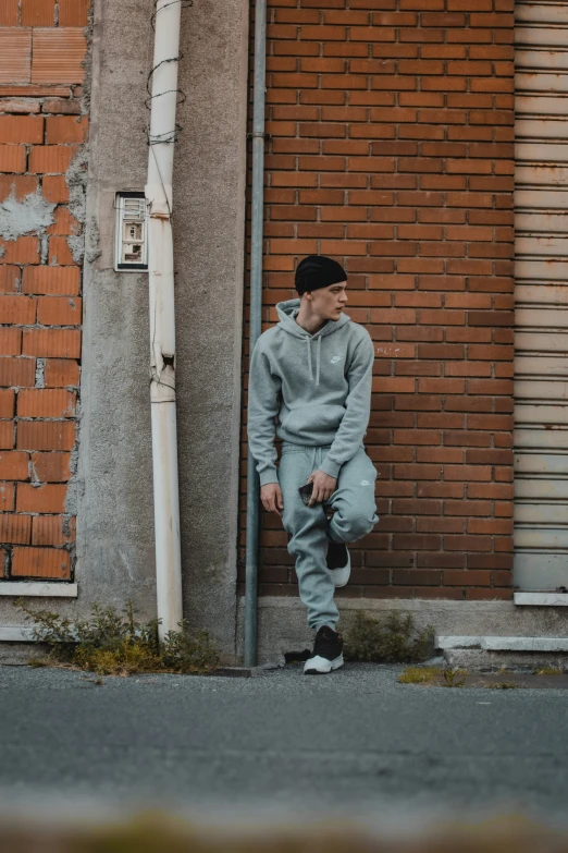 man sitting on the curb in front of brick wall