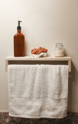 a towel, soap and a container sit on the shelf