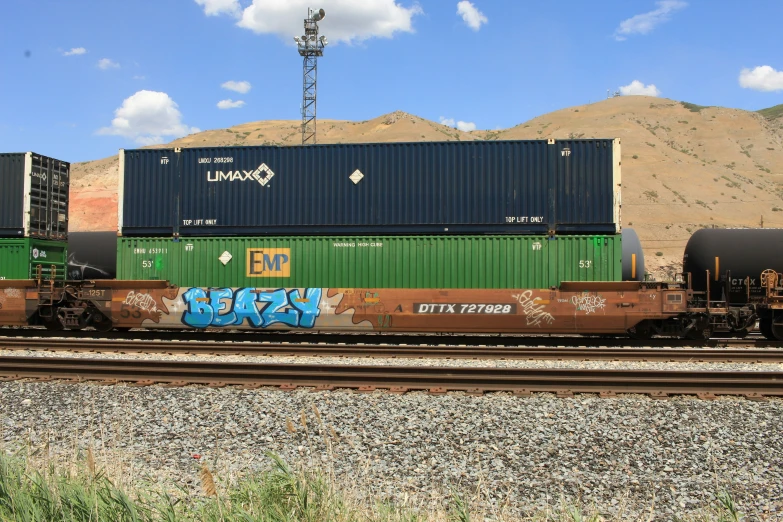 a train with graffiti on the side of it going down tracks