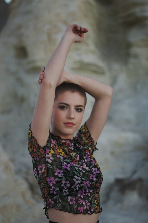 a girl is posing for the camera with a rock in the background