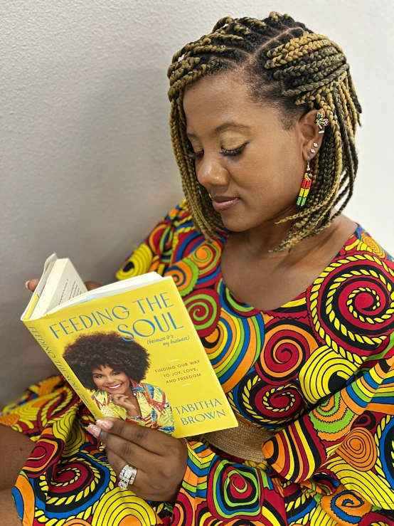 a lady in brightly colored dress holding a book