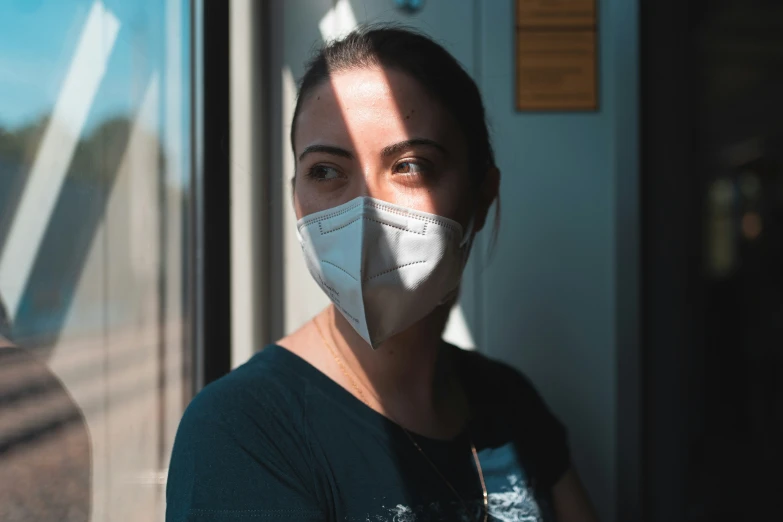 a woman with a mask on looking out the window