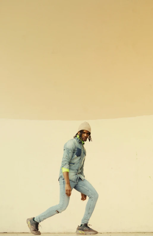 a young man wearing a hat and walking on a skateboard