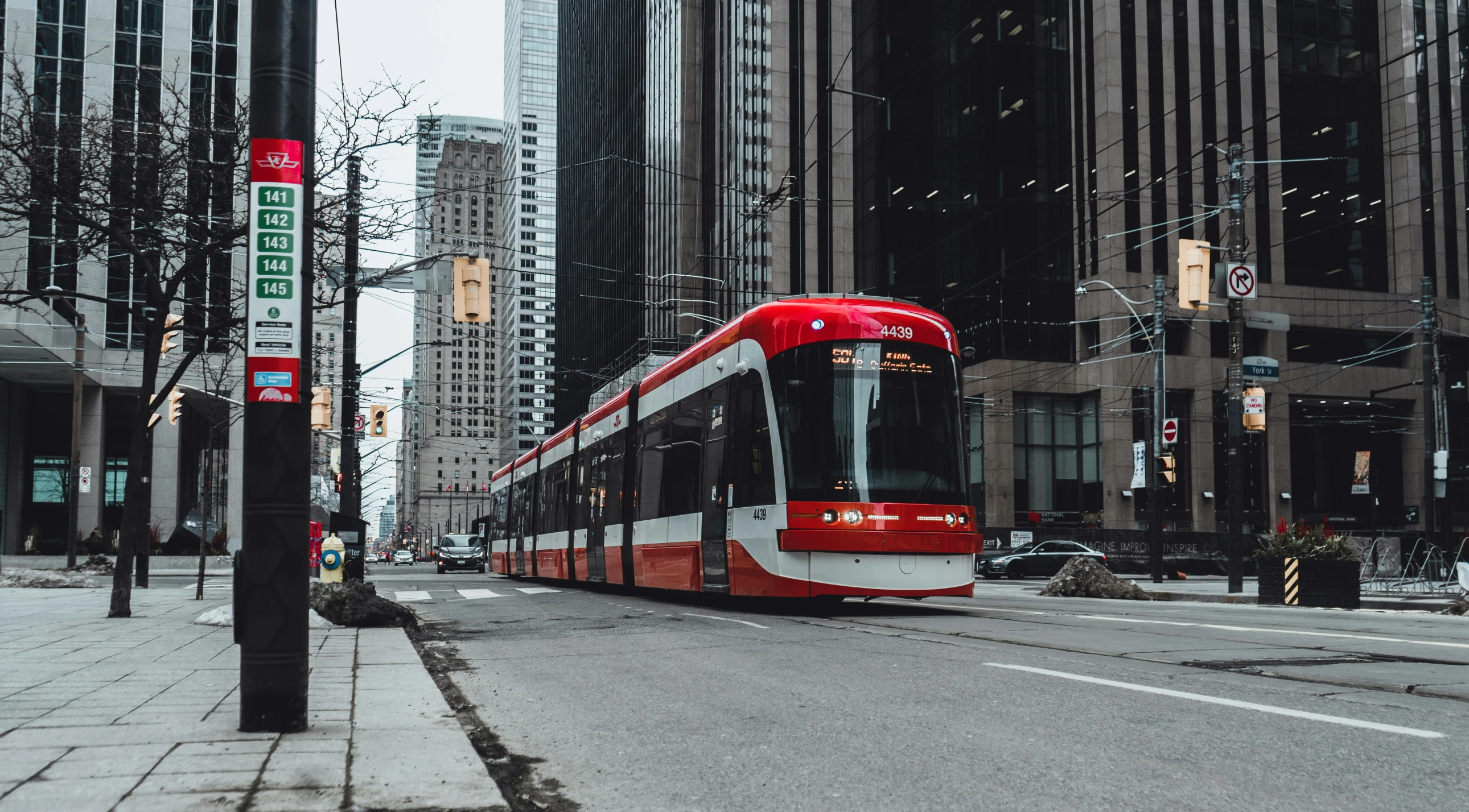 a red and white subway car stopped at a curb