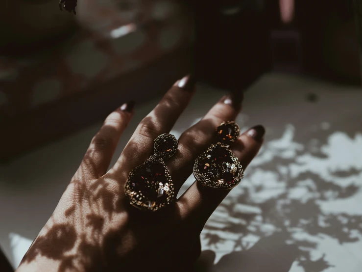a woman with long nails and yellow nail polish is wearing two earrings