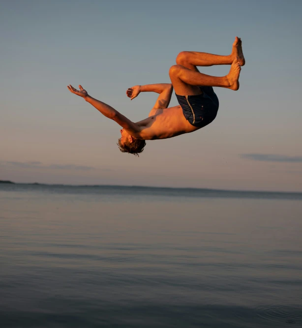 the man is jumping in the air near the water