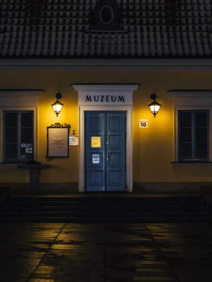 the front entrance to muzenum restaurant lit up by night