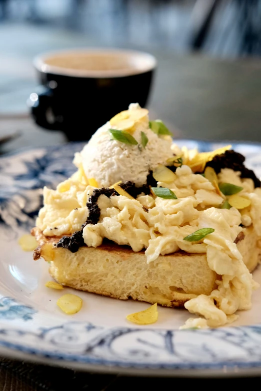 an odd pastry with ice cream on a plate next to some cups of coffee