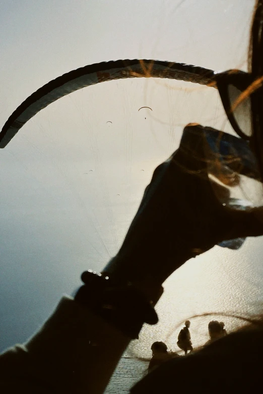 the person holds on to the paraglider strings near water