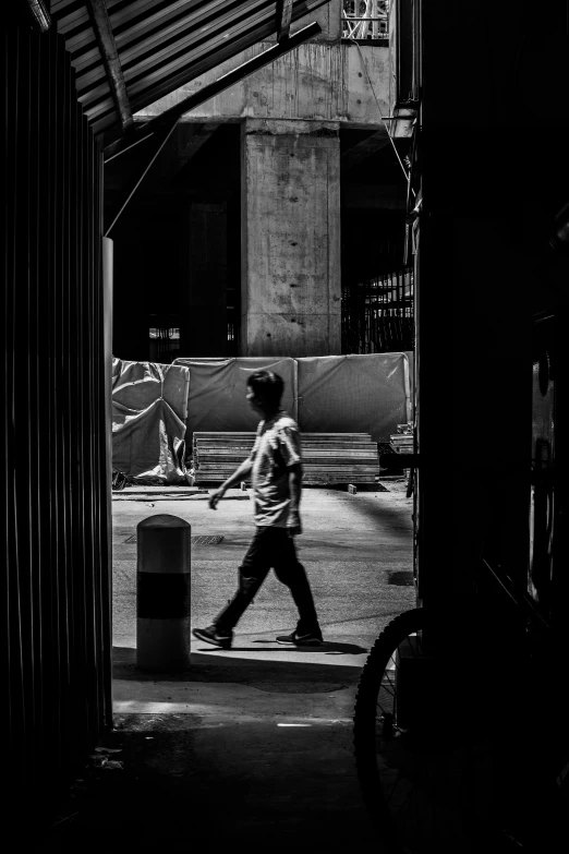 a man walking down the middle of a walkway near buildings