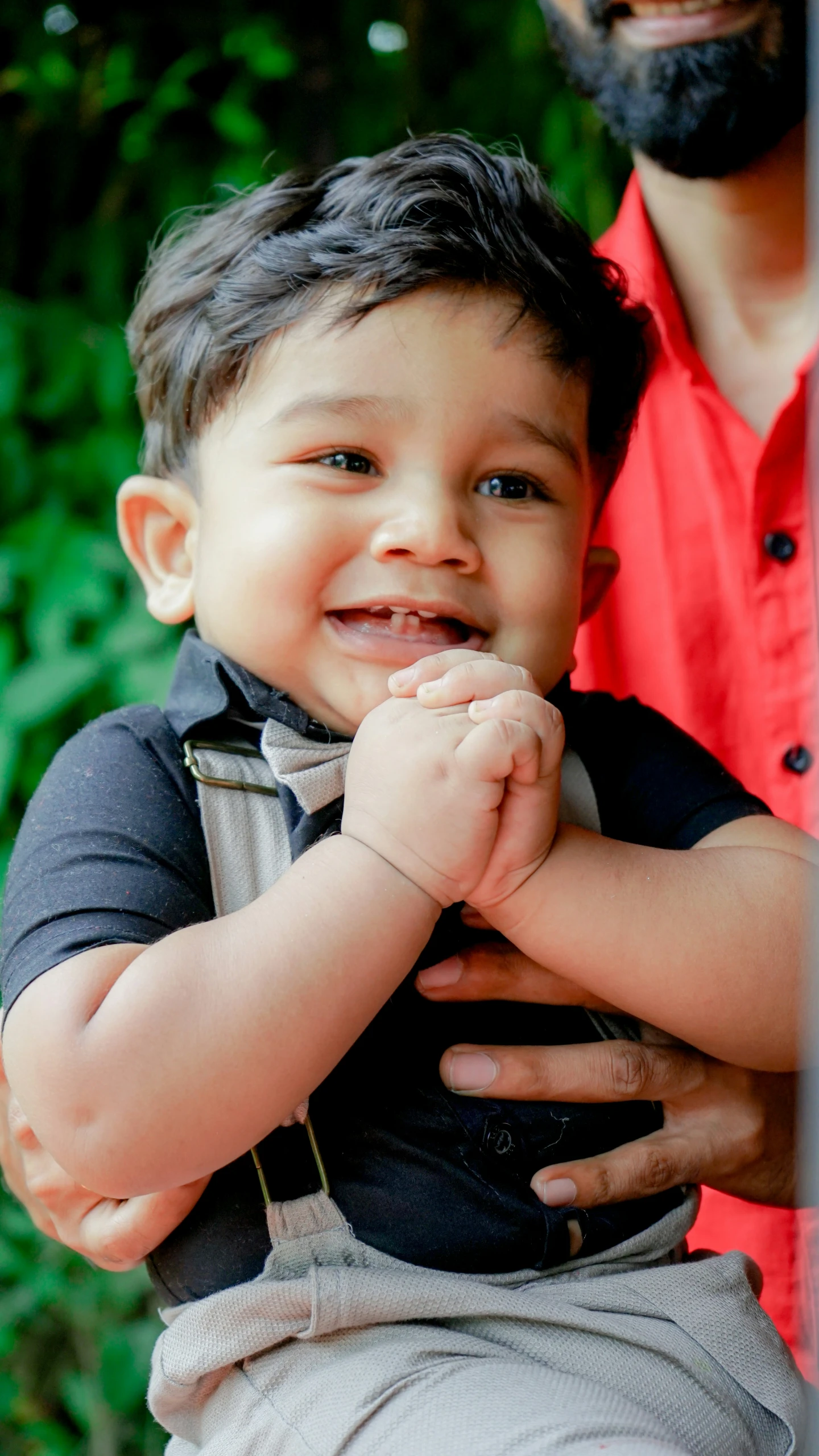 a smiling little boy holding his fathers arm