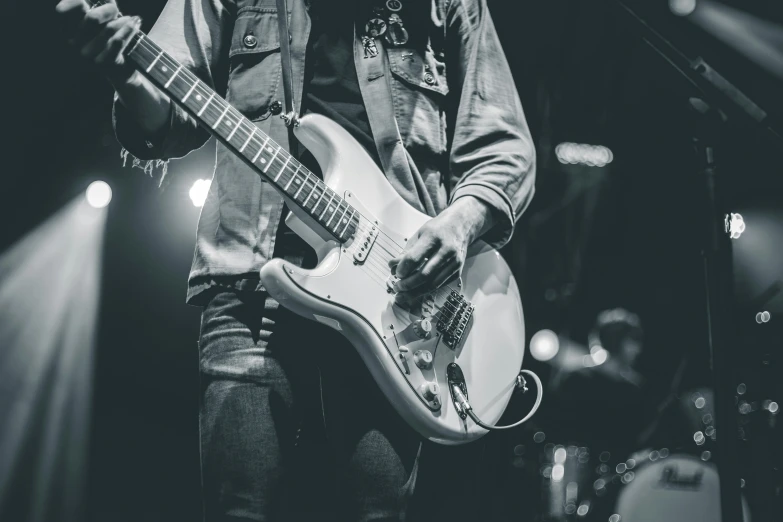 a guy in jacket playing a guitar in front of a microphone