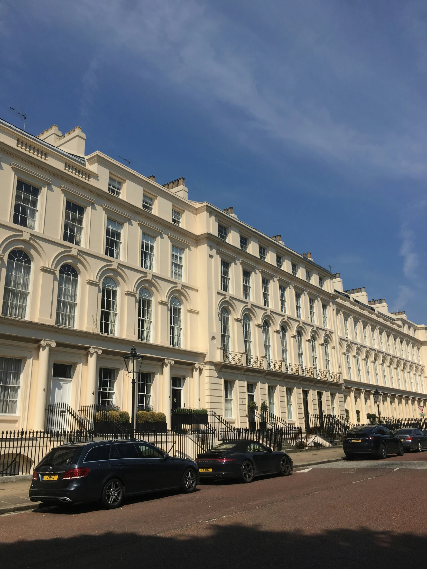 cars parked outside an old building in the sunshine