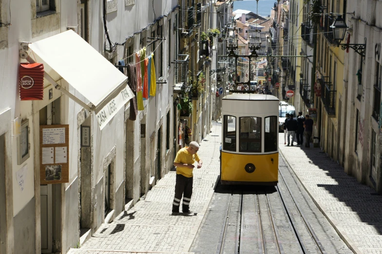 a man in a yellow shirt standing next to a trolley car