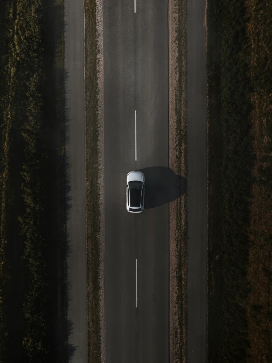 an overhead view of two cars driving down a long road