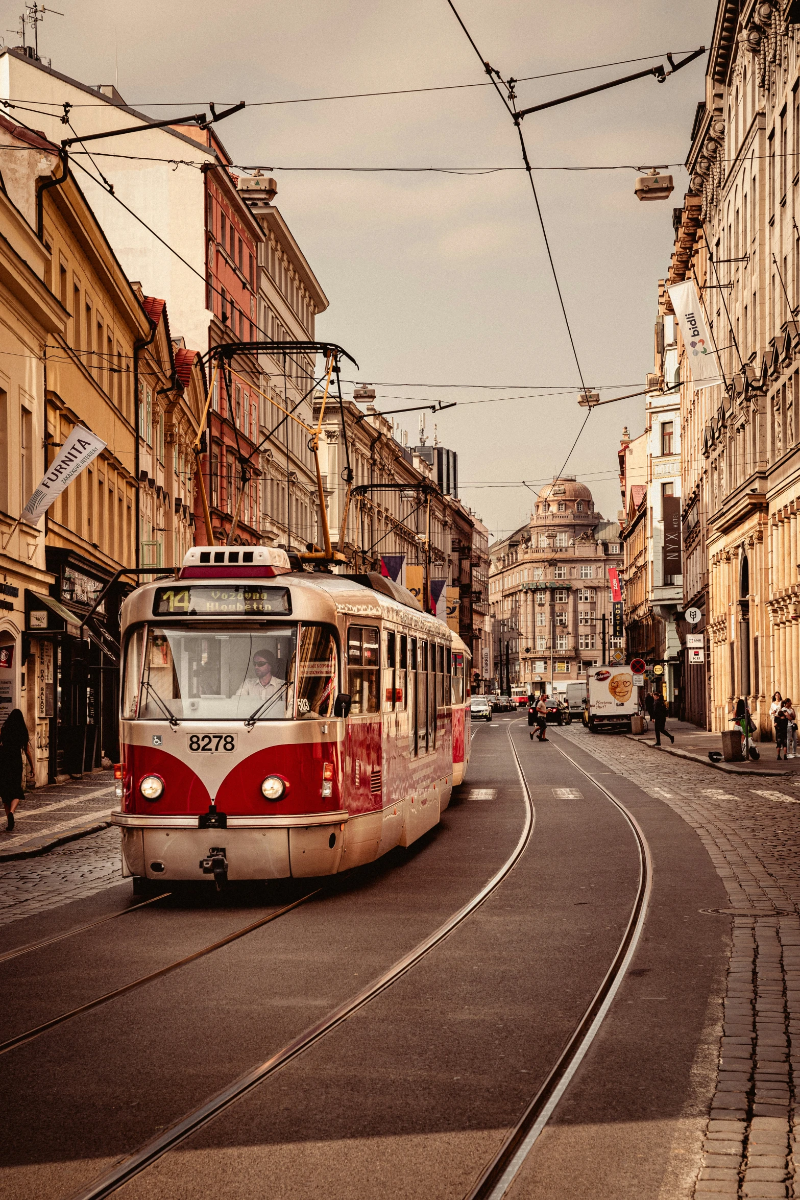 a train drives down the street between two buildings