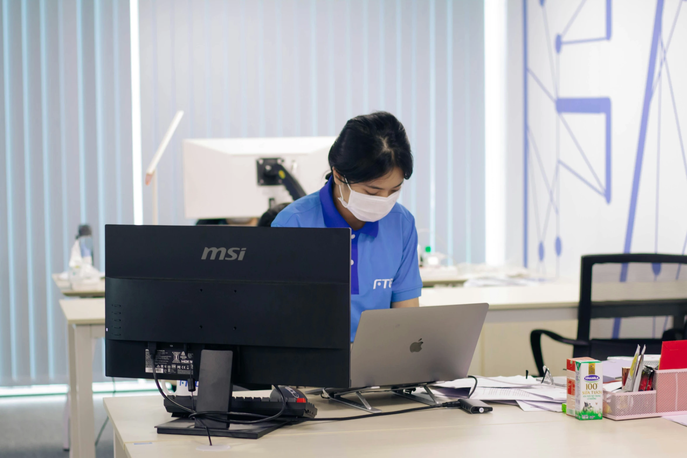 a woman wearing a face mask on her laptop