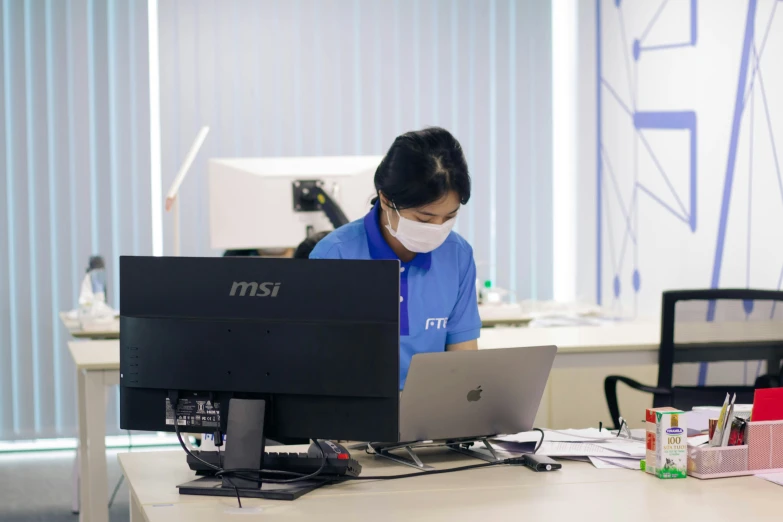 a woman wearing a face mask on her laptop