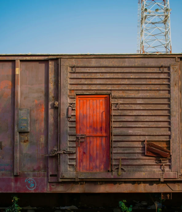 an old rusted out train car with a red door