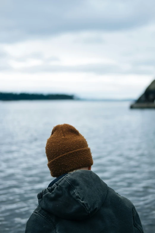 a boy sitting on a stone wall overlooking the water