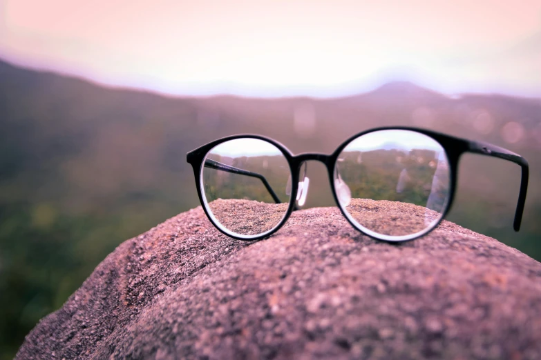 a pair of round glasses sitting on top of a rock