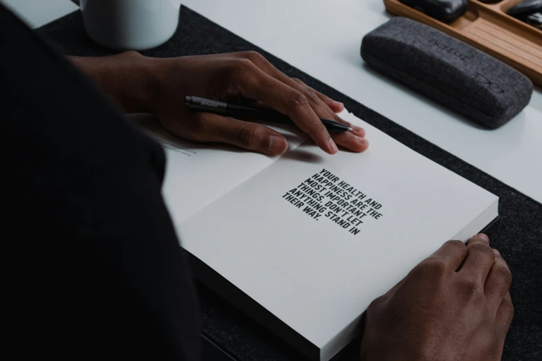 a person sitting on a bed in front of a book and pen