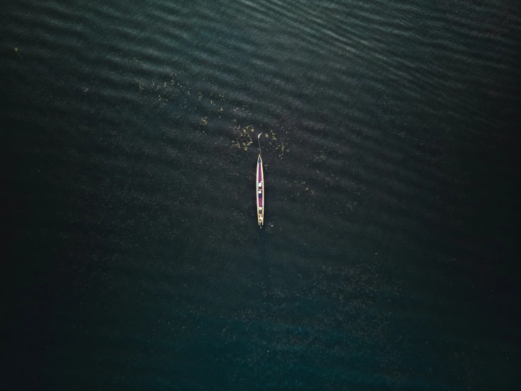 a single single white boat floating on top of the ocean