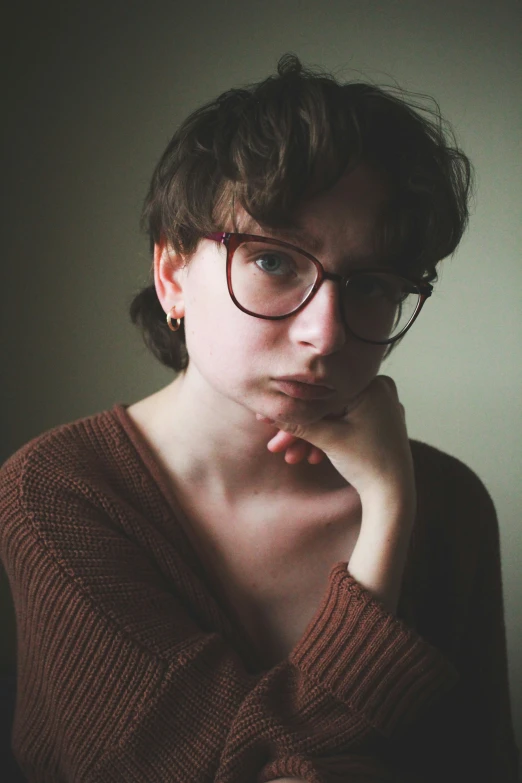 a young lady in a brown sweater has her hands on her face