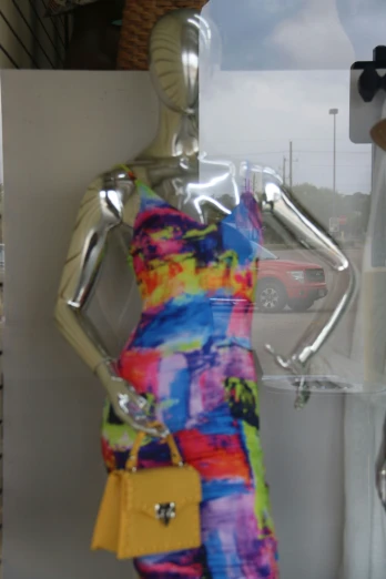 a dress on display in a window with a handbag