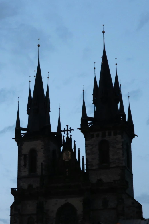 a tower with several spires and clocks lit up by the sun