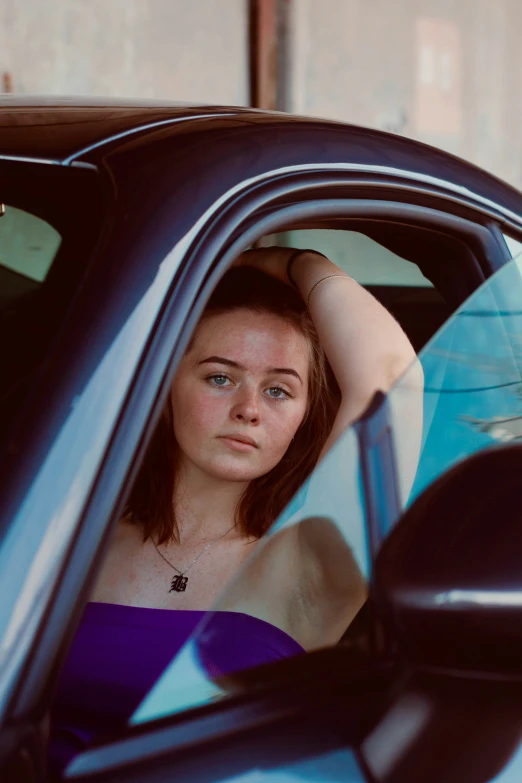 a woman wearing a purple shirt in a blue car