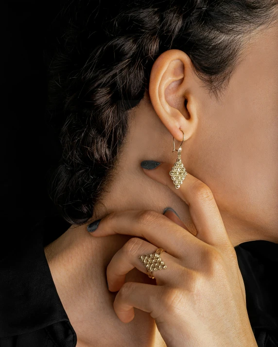 a woman with dark hair wearing some gold earrings