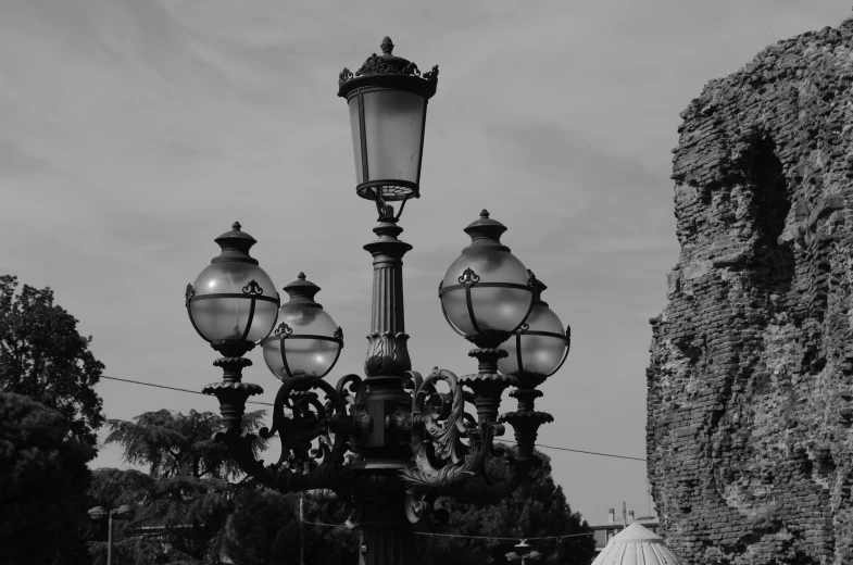 two lamp post lights at the end of a walkway near an old stone castle