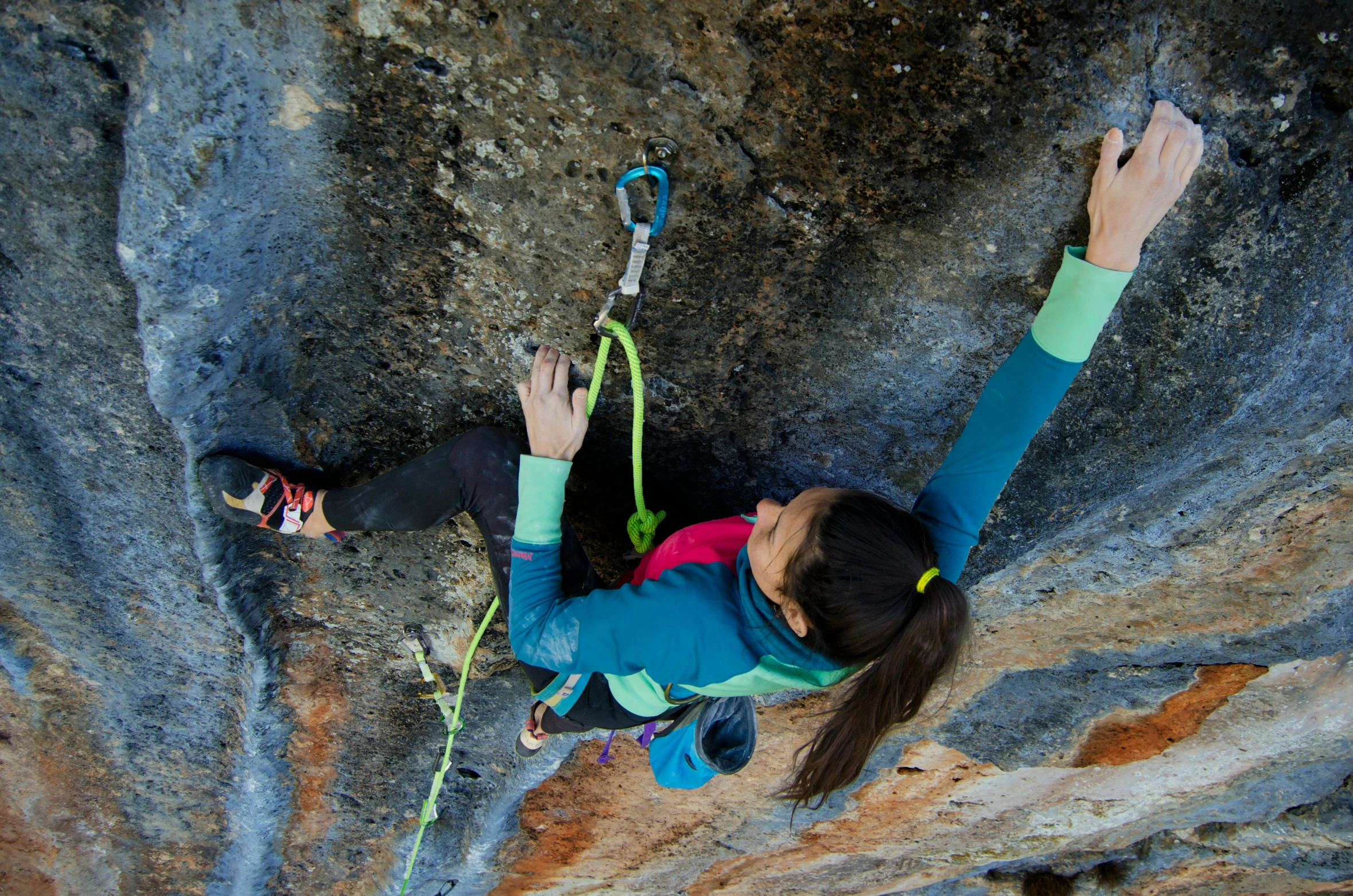 a woman climbing up a steep mountain holding on to a rope