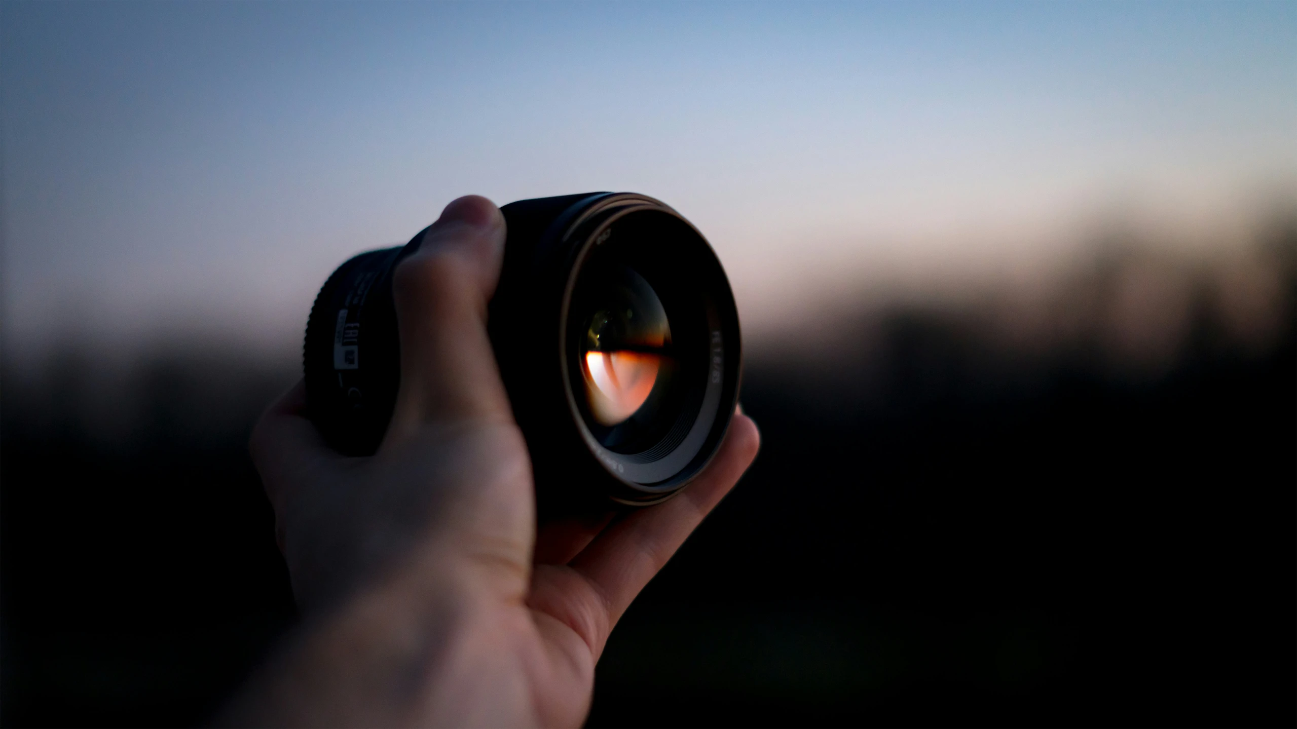 a person holding a lens in their left hand, taking a po