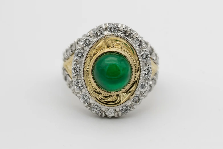 a ring with green stone surrounded by diamonds