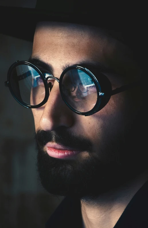 man with glasses standing in dark room at night